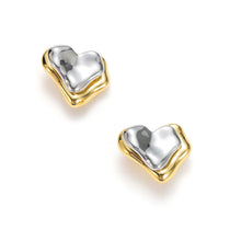 Load image into Gallery viewer, Two-tone layered heart stud earrings featuring a polished gold heart in front and a sculptural silver heart ear jacket behind the earlobe for a modern statement look.
