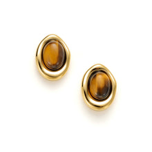 Load image into Gallery viewer, Gold sculpted oval stud earrings featuring genuine tiger's eye gemstones with a smooth flowing bezel design on a white background.
